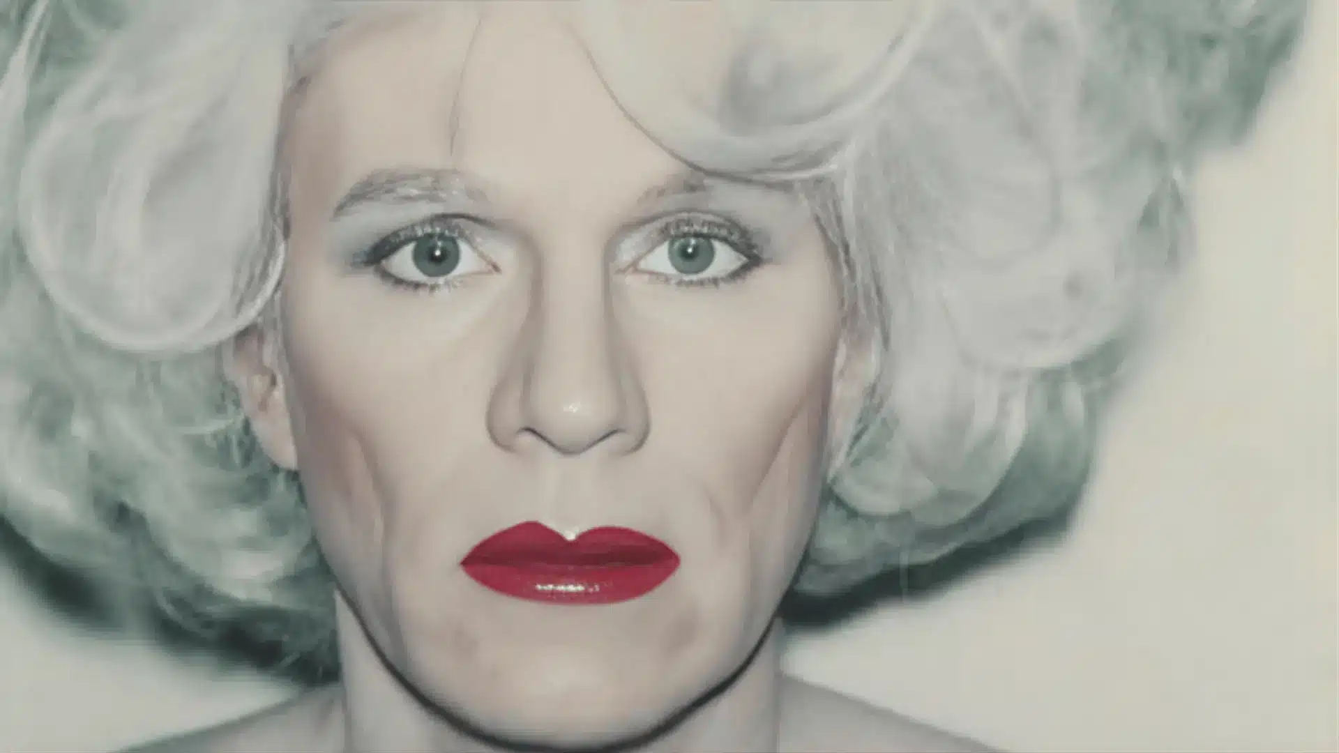 A woman with striking white hair and red lipstick, reflecting the vibrant pop art aesthetic of Andy Warhol’s self-portrait.