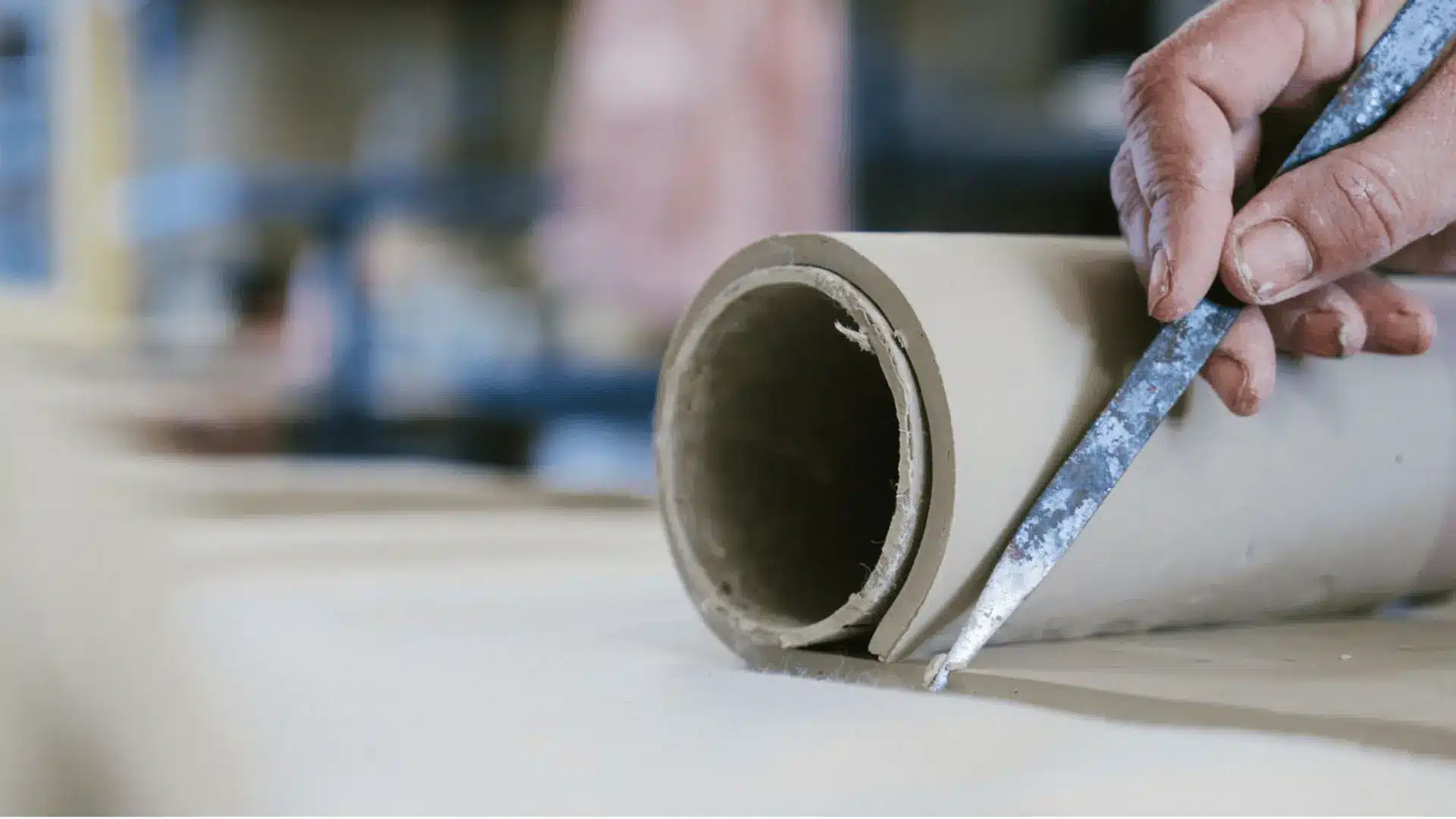 a person using a simple tool for shaping a clay slab