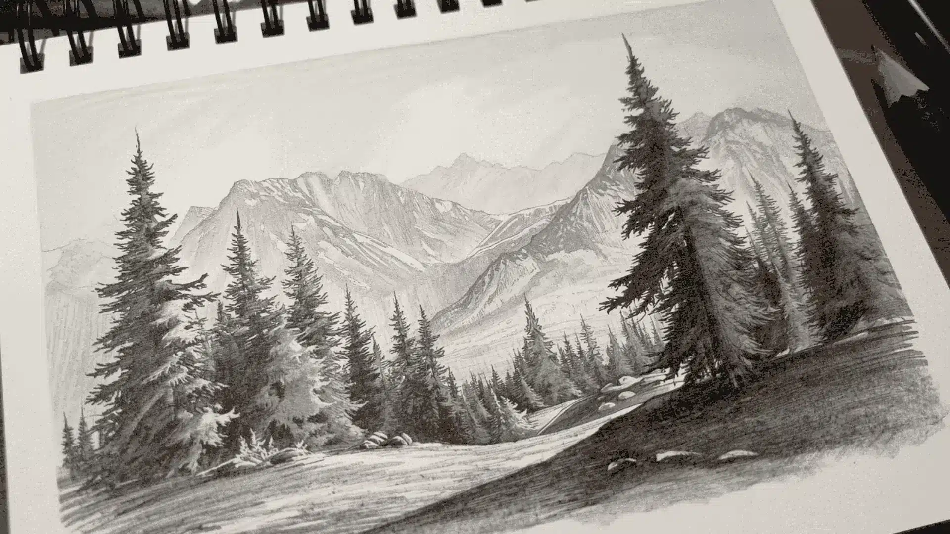 Pencil landscape with sharp, dark foreground and lighter, softer distant mountains fading into haze