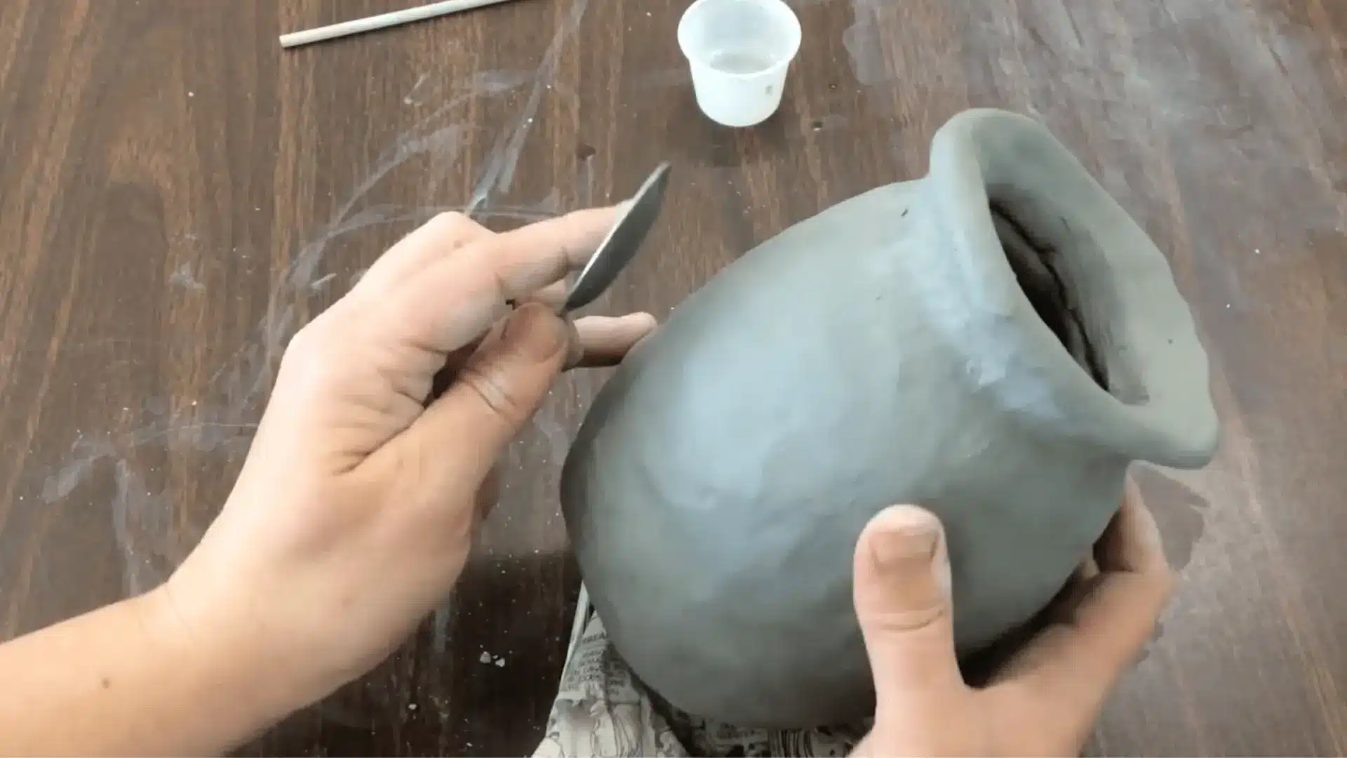  a person smoothing a clay pot with a stone surface 