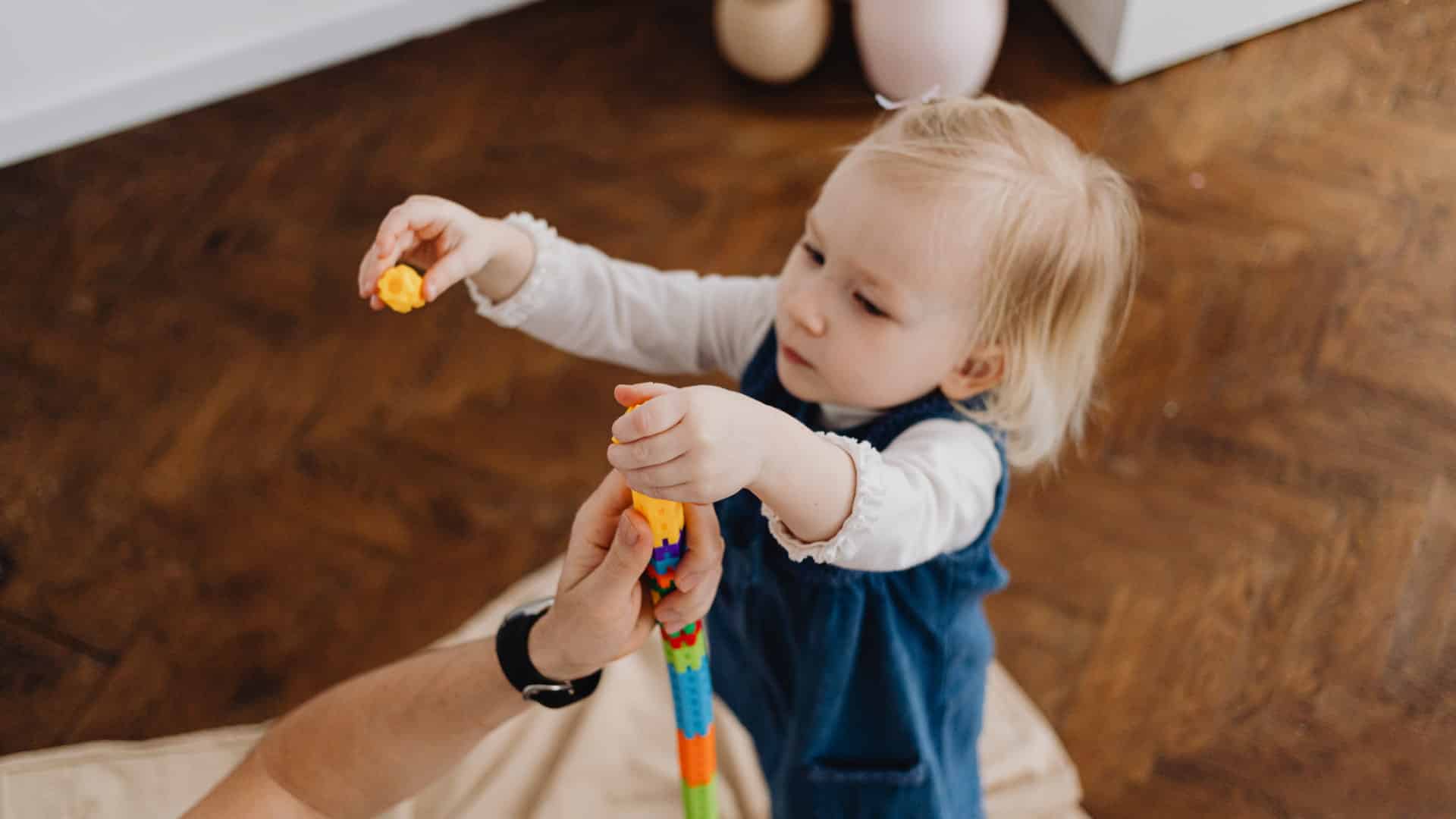 Toddler stacking colorful building toys with a parent