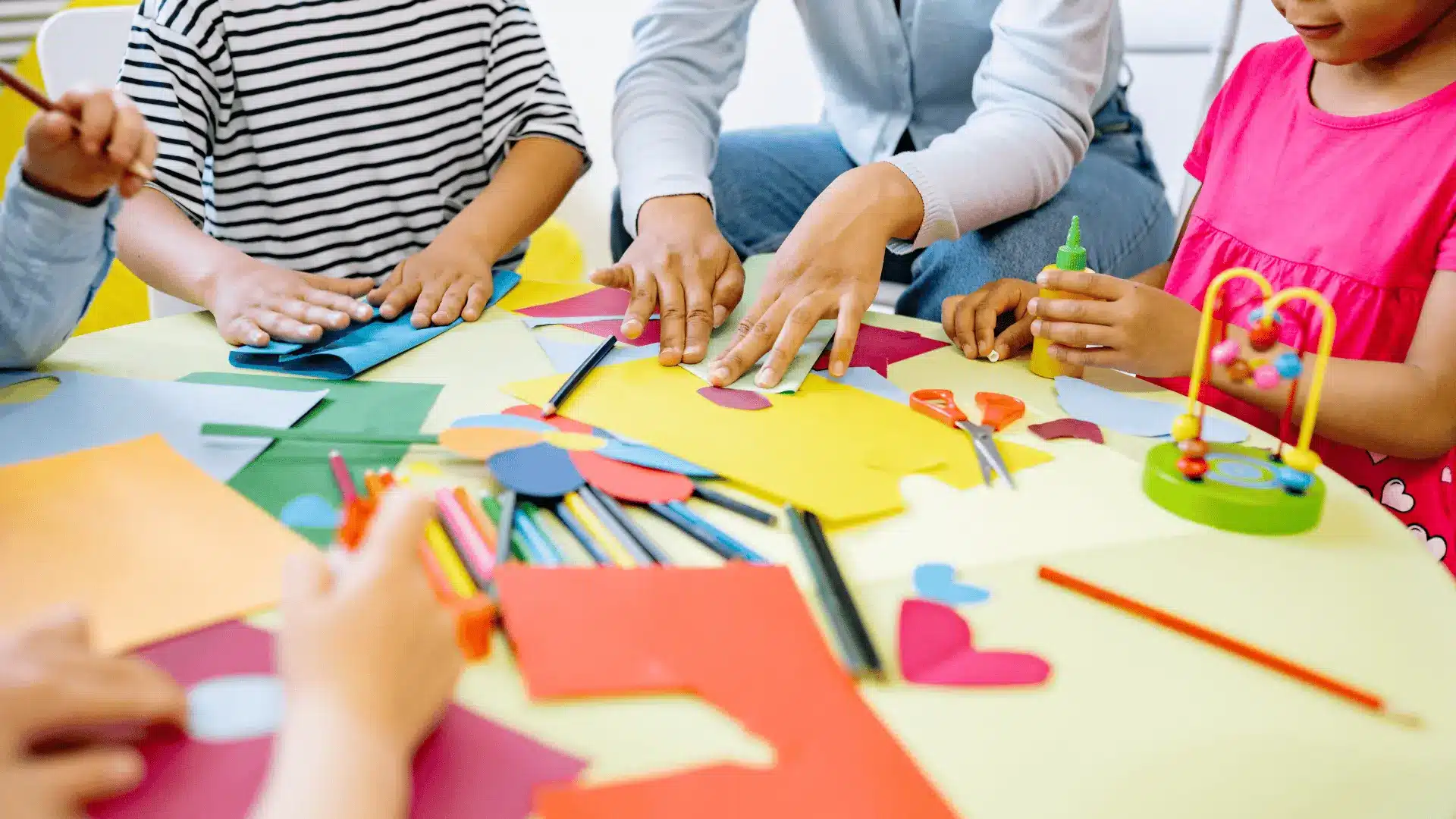 Children and adults focused on various crafts at a table, illustrating a hands-on approach to a homeschool art curriculum.