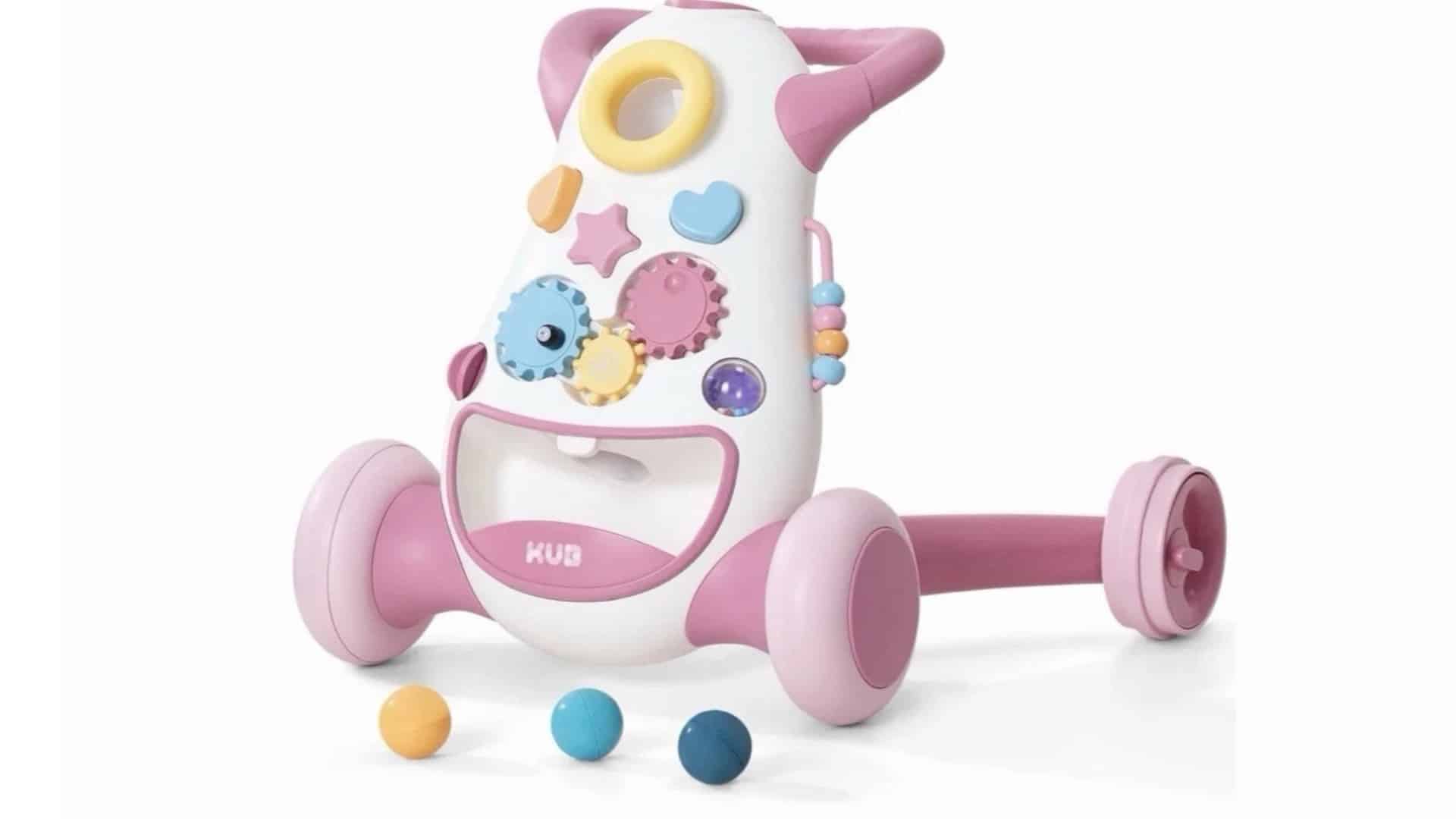 KUB baby push walker in white and pink with wide wheels, front activity gears, and three play balls on a white background.