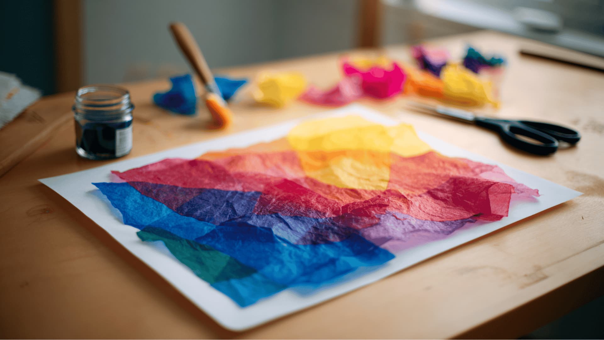 Vibrant tissue paper collage with stained glass color effect on the art desk with torn tissue pieces and foam brush