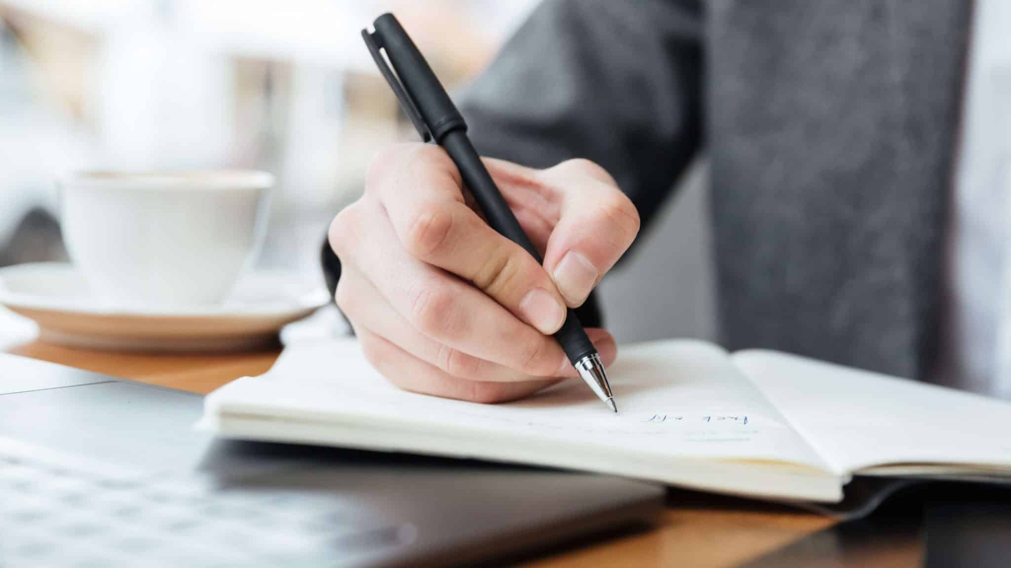 Person setting aside their phone and writing in a journal during a digital detox challenge